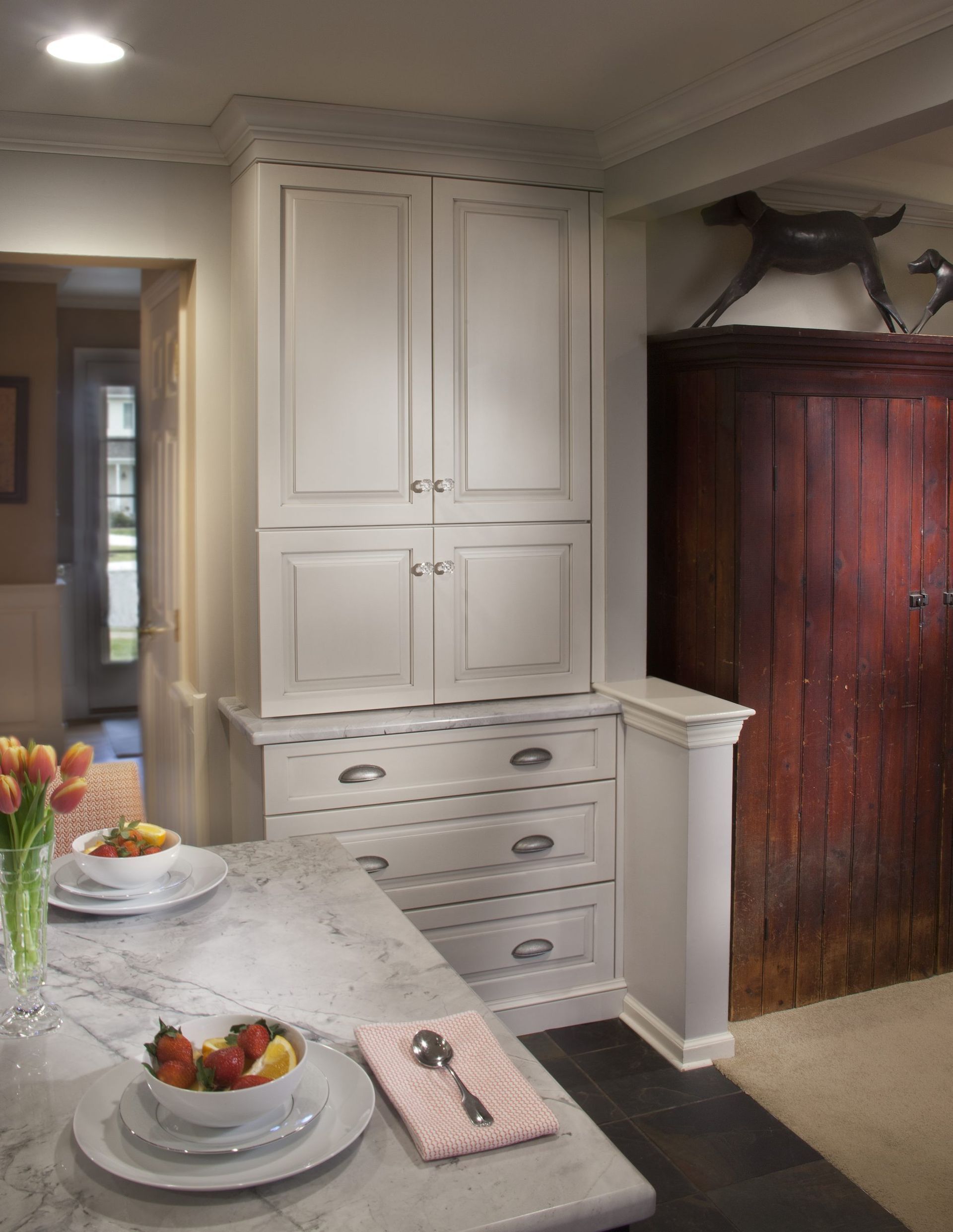 A kitchen with white cabinets and a bowl of fruit on the counter