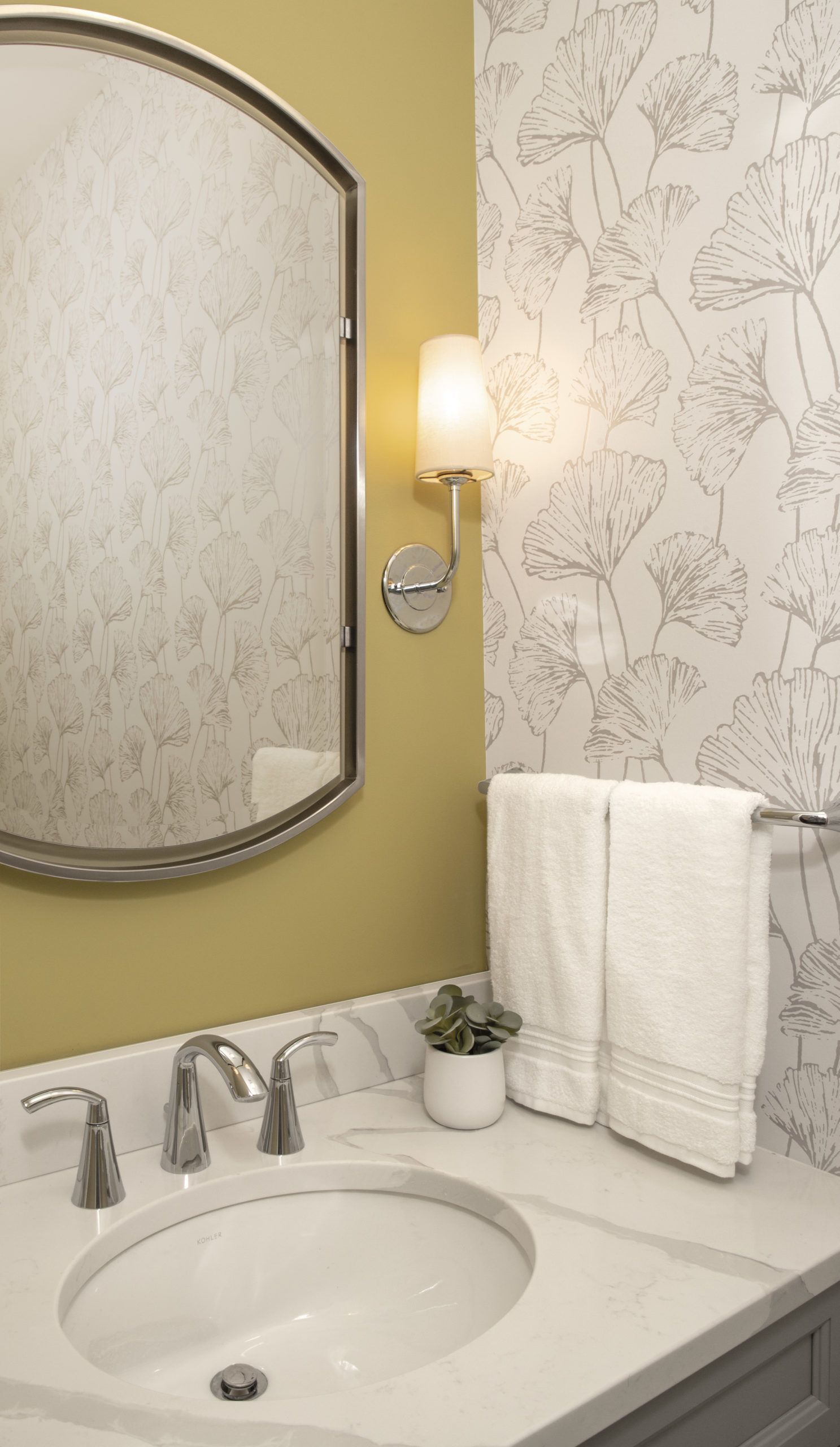 A bathroom with a sink , mirror , and towels.