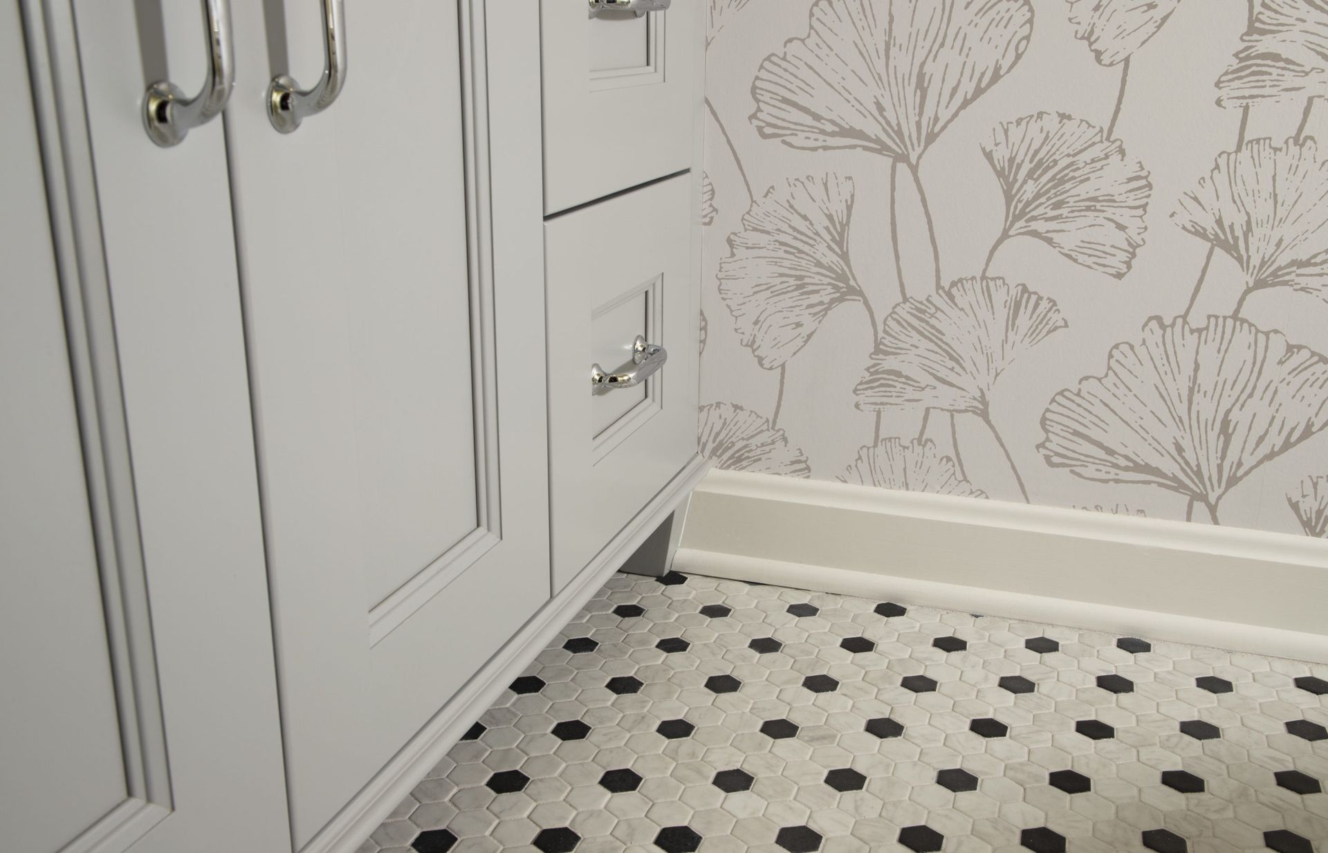 A bathroom with white cabinets and a black and white tile floor.