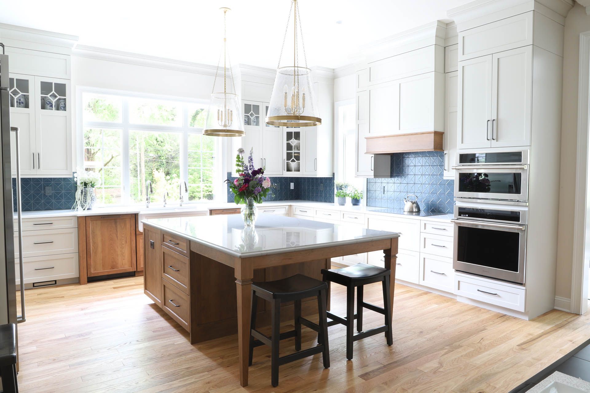 Bright white modern kitchen with island, wood floors, and stainless steel appliances