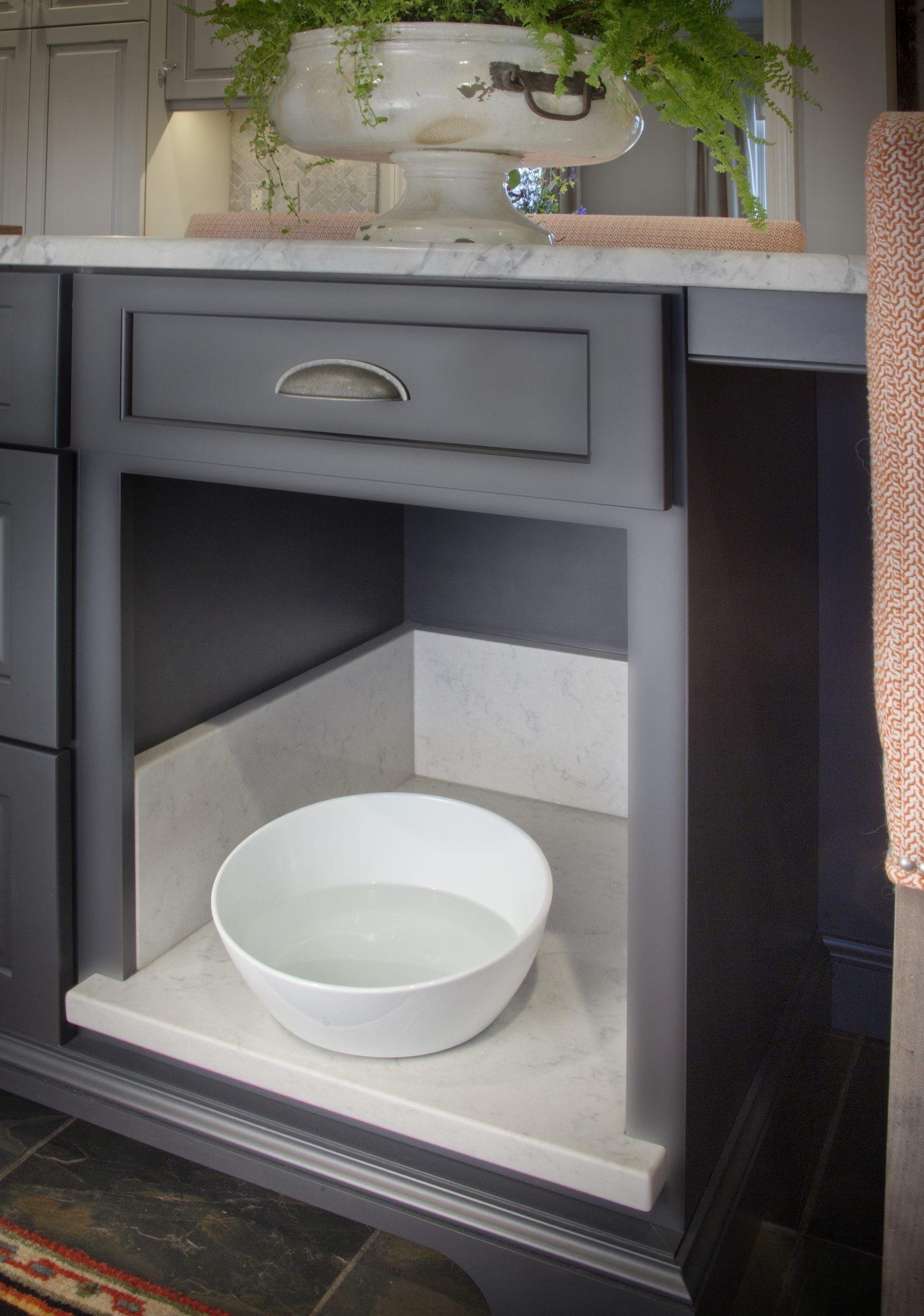 A white bowl is sitting under a drawer in a bathroom.