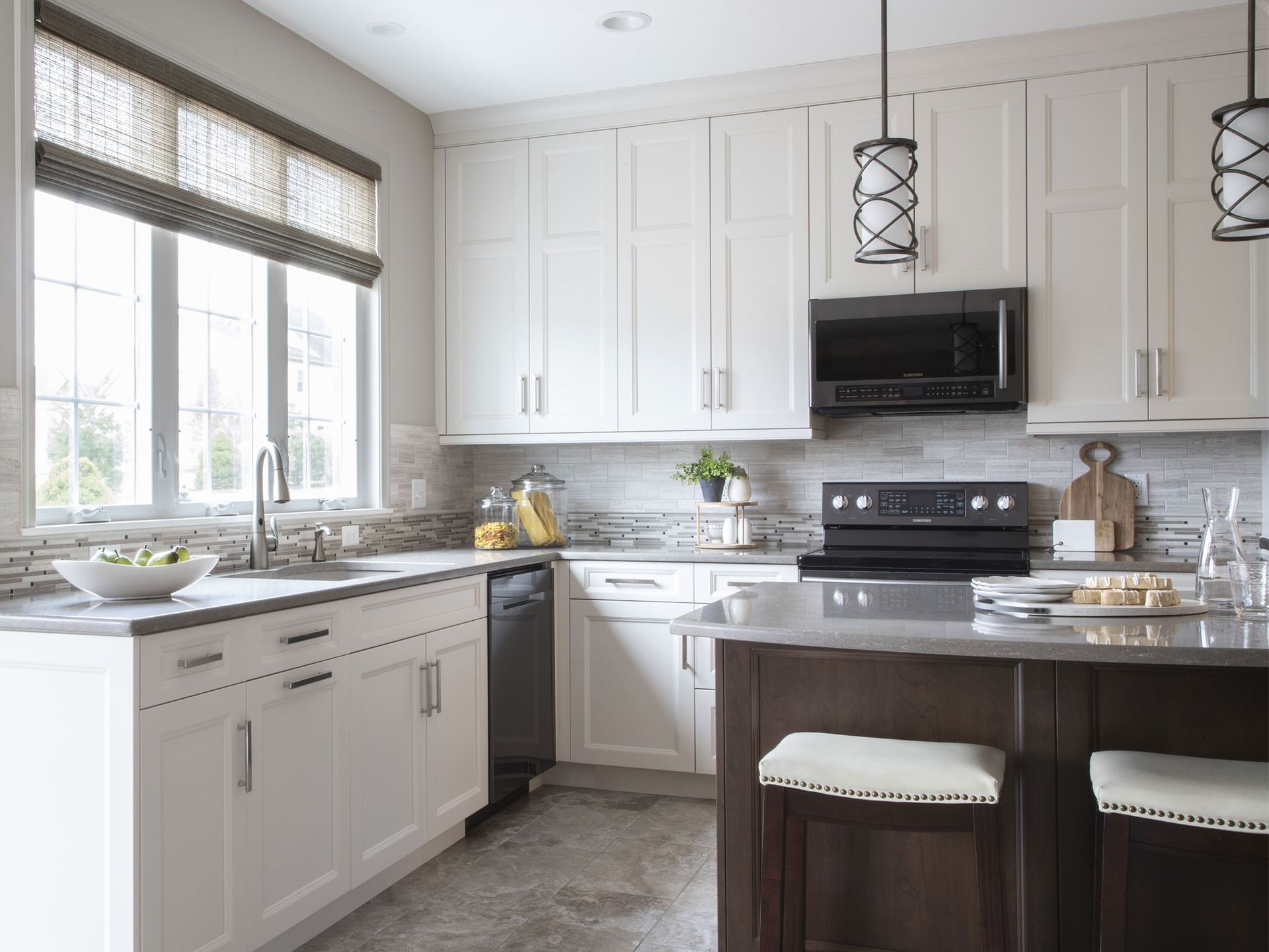 Modern kitchen by KBE Design Build with white cabinets, dark island, and a window.