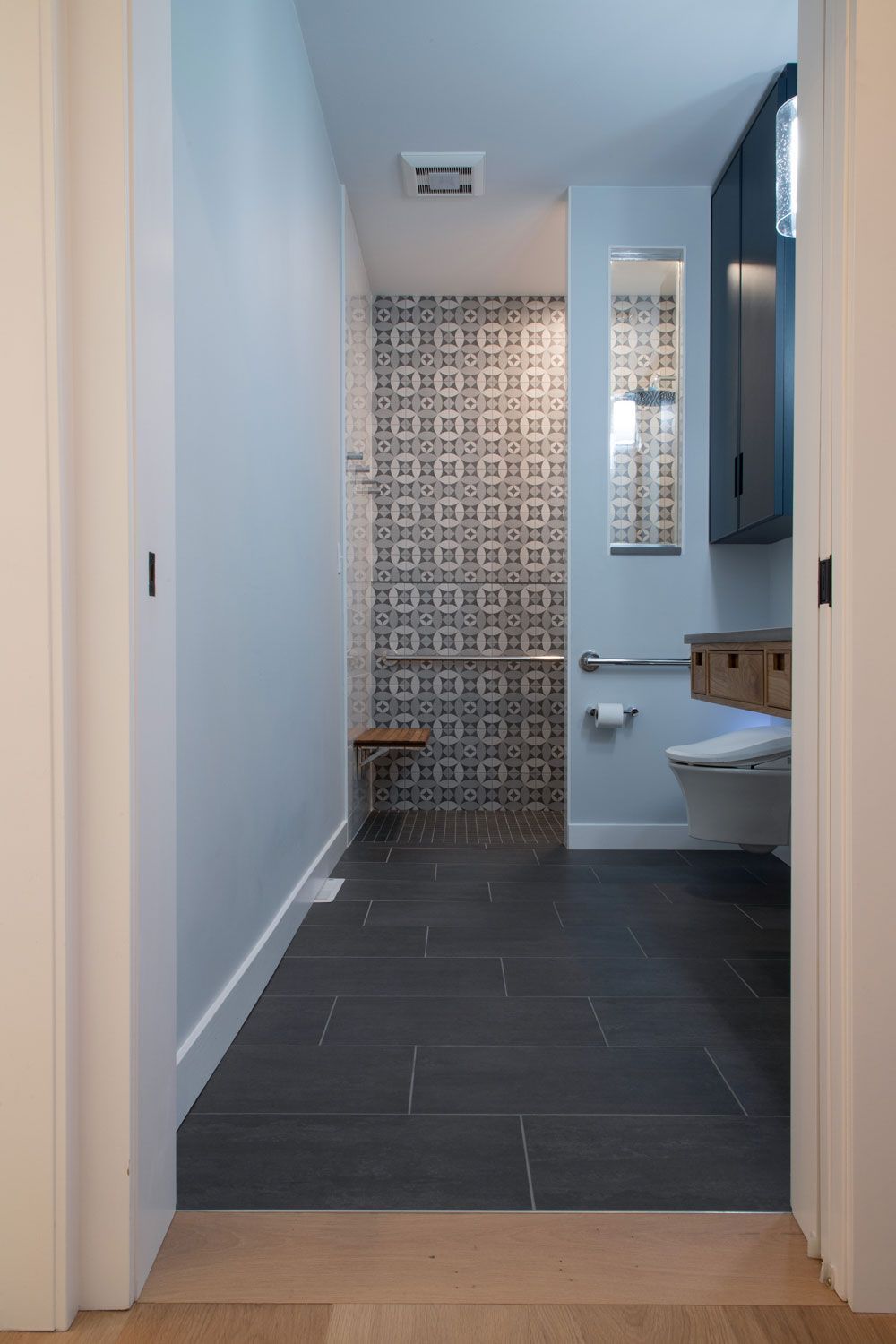 An ADA complaint bathroom  hallway leading to a bathroom with a toilet and a sink.