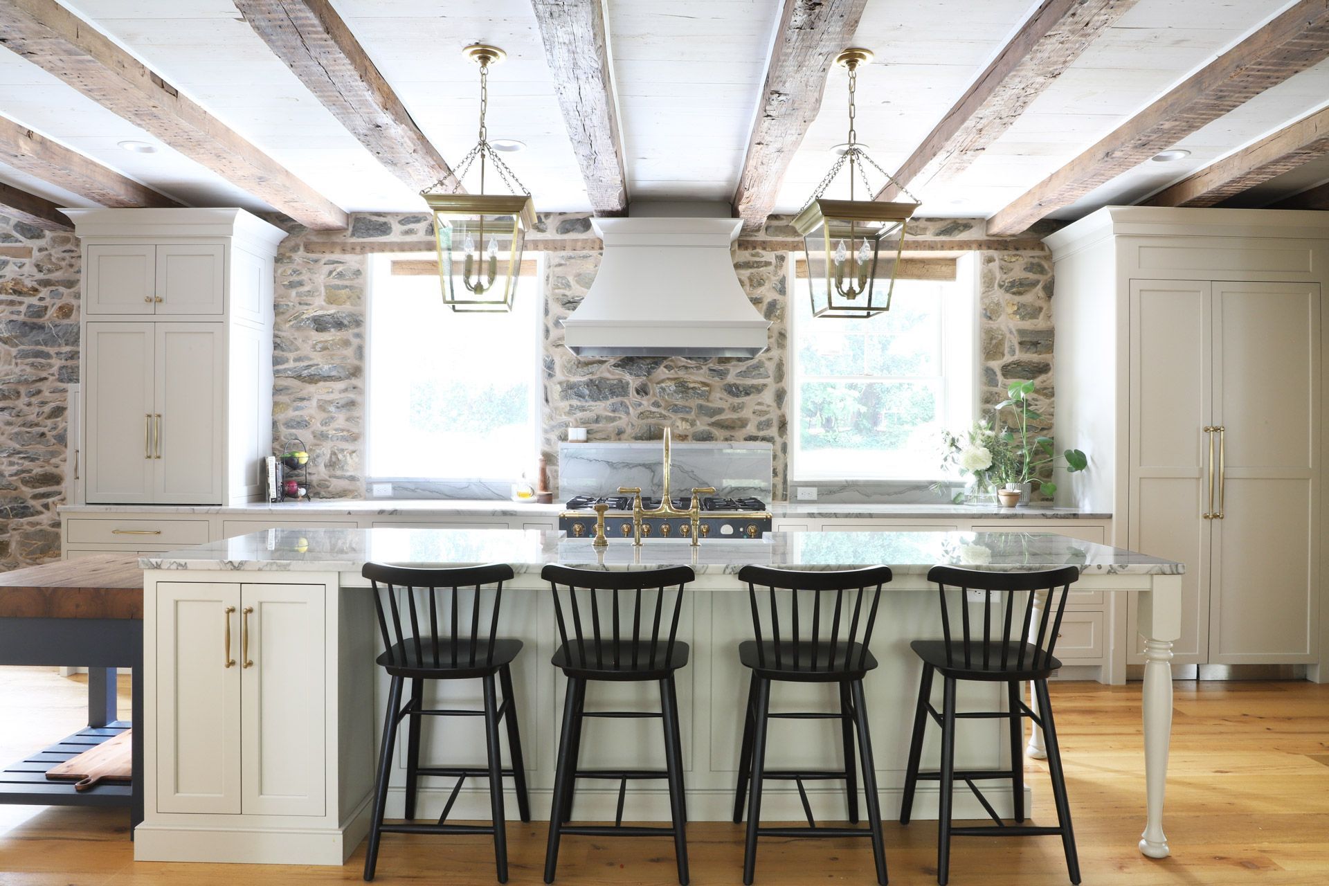Cherry-wood kitchen with island, white countertops, stainless steel appliances, and bar stools.