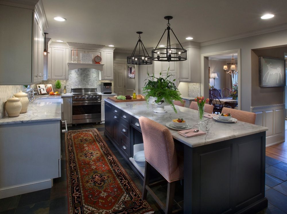 A kitchen with a large island in the middle and a rug on the floor.