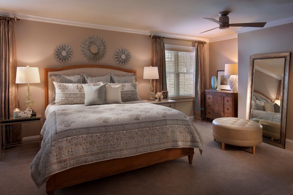 A bedroom with a bed , dresser , mirror and ceiling fan.