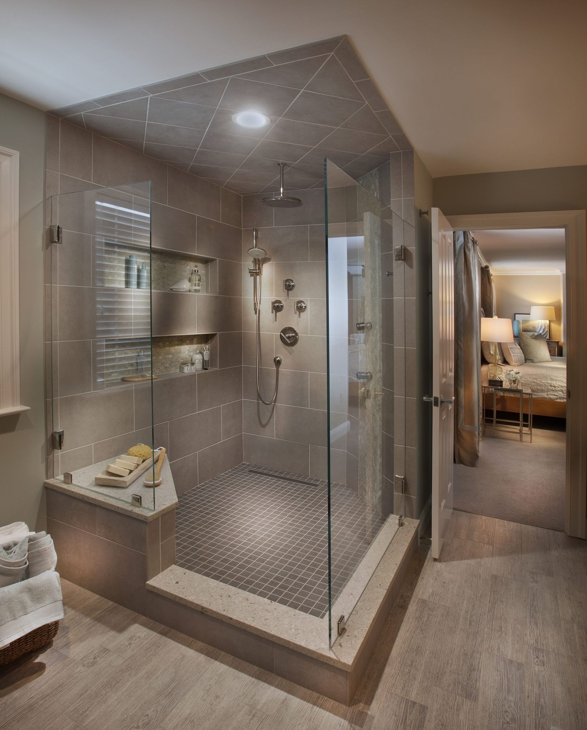 A bathroom with a walk in shower and a bedroom in the background