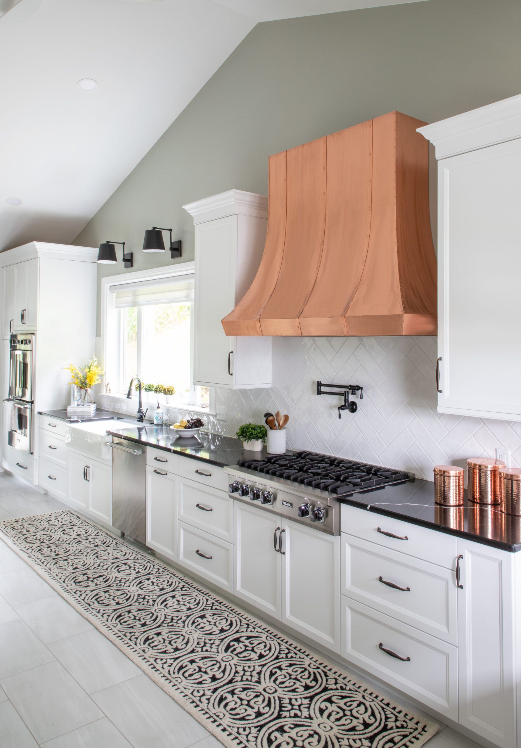 A kitchen with white cabinets and a copper hood