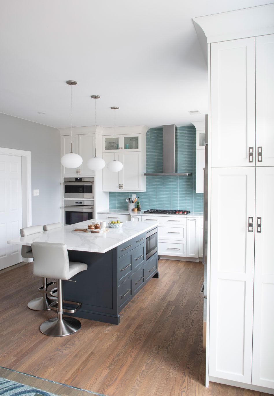 A kitchen with white cabinets and a large island in the middle.