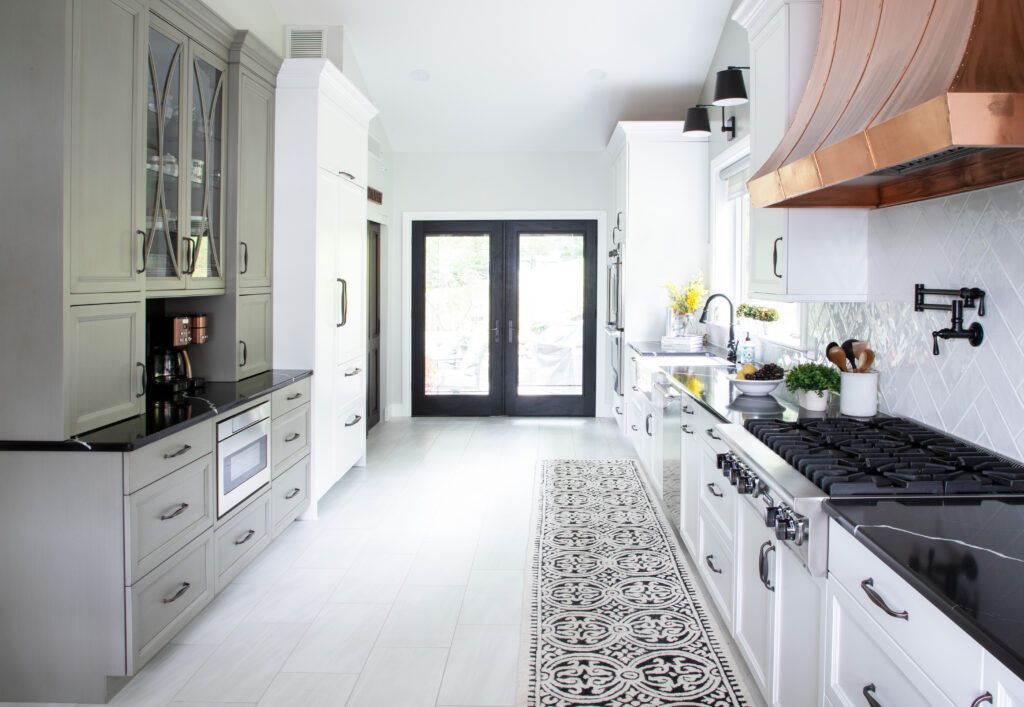 A kitchen with white cabinets and a copper hood