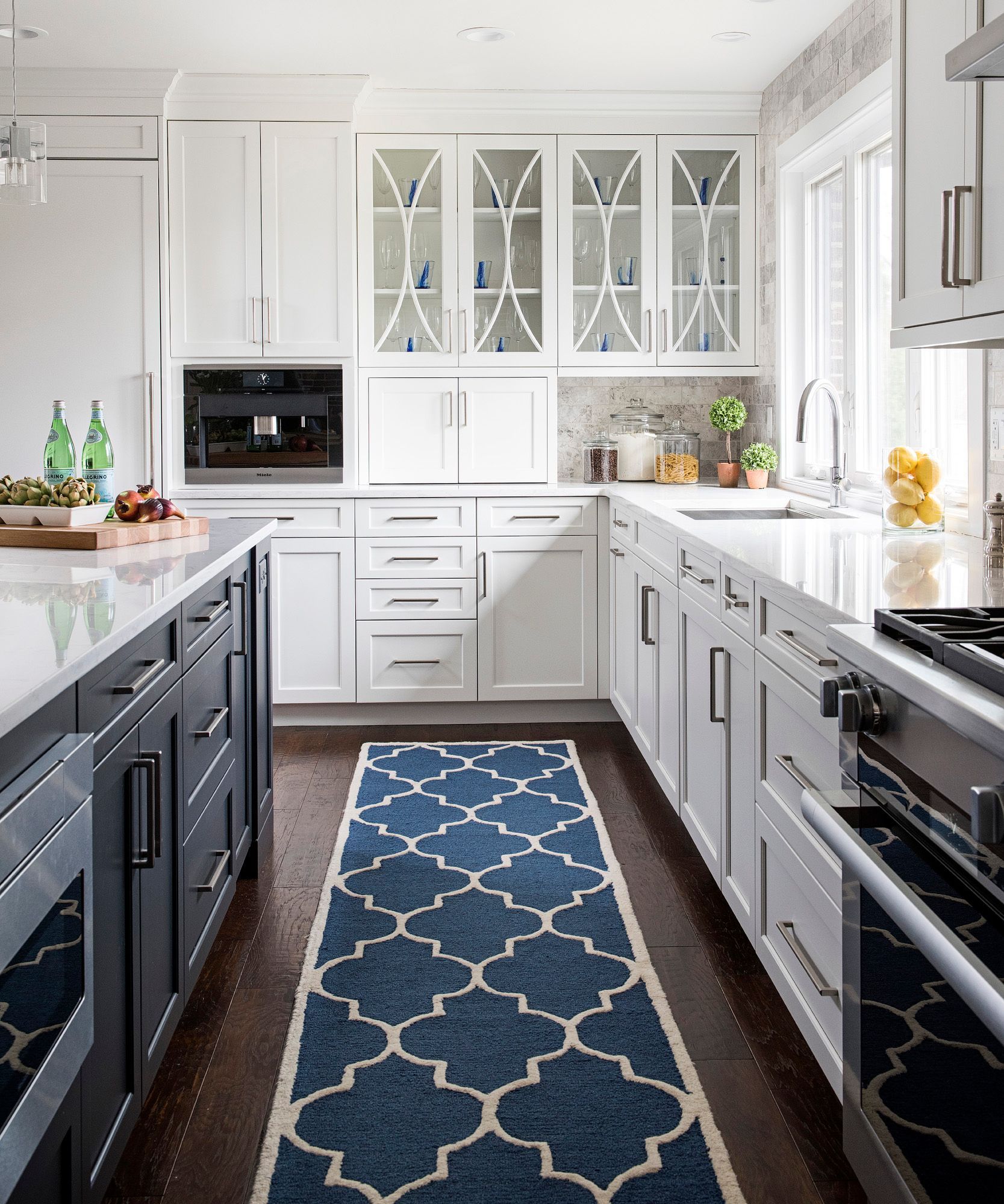 A kitchen with white cabinets and a blue rug on the floor.