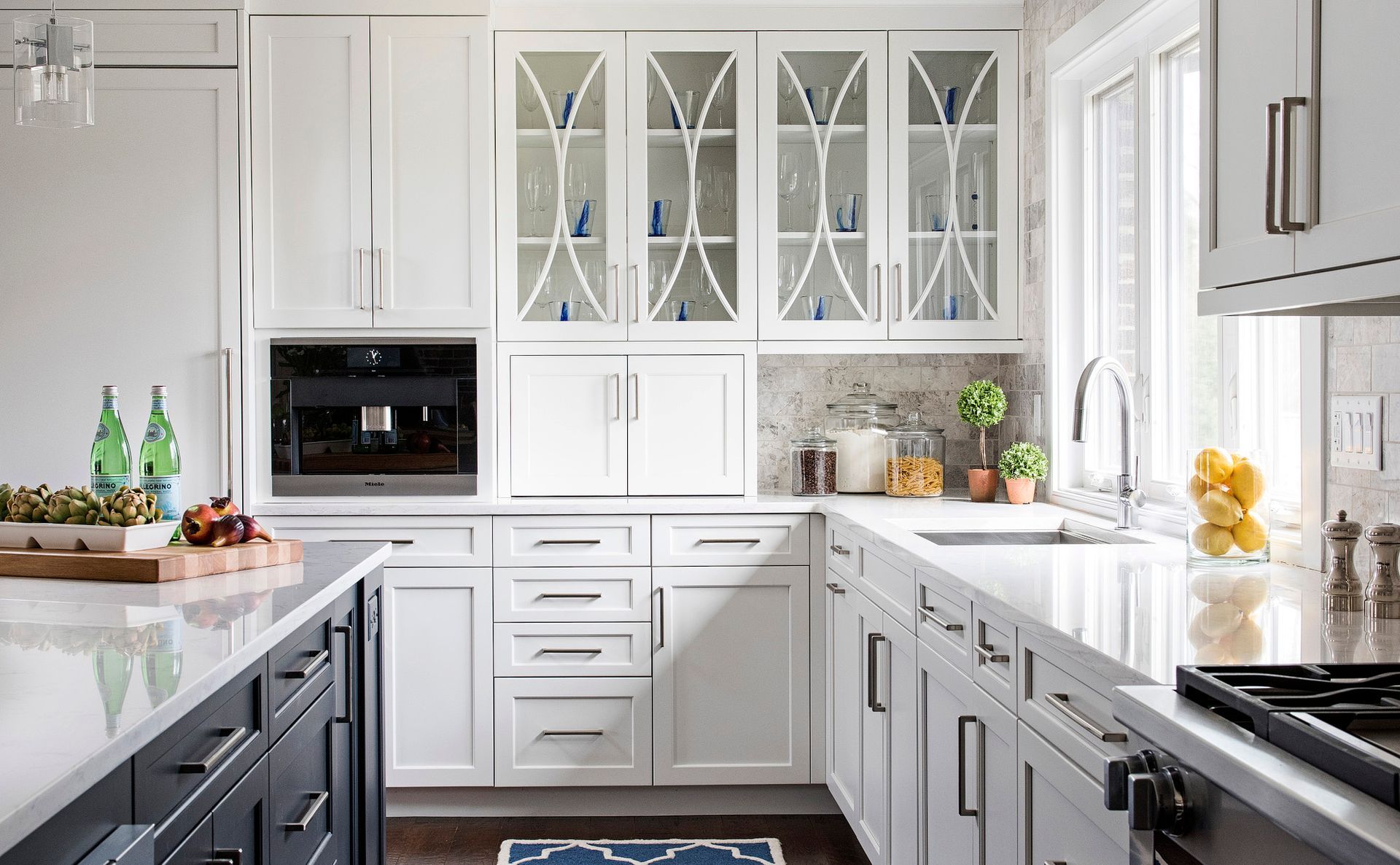 A kitchen with white cabinets , black counter tops , a sink , and a window.
