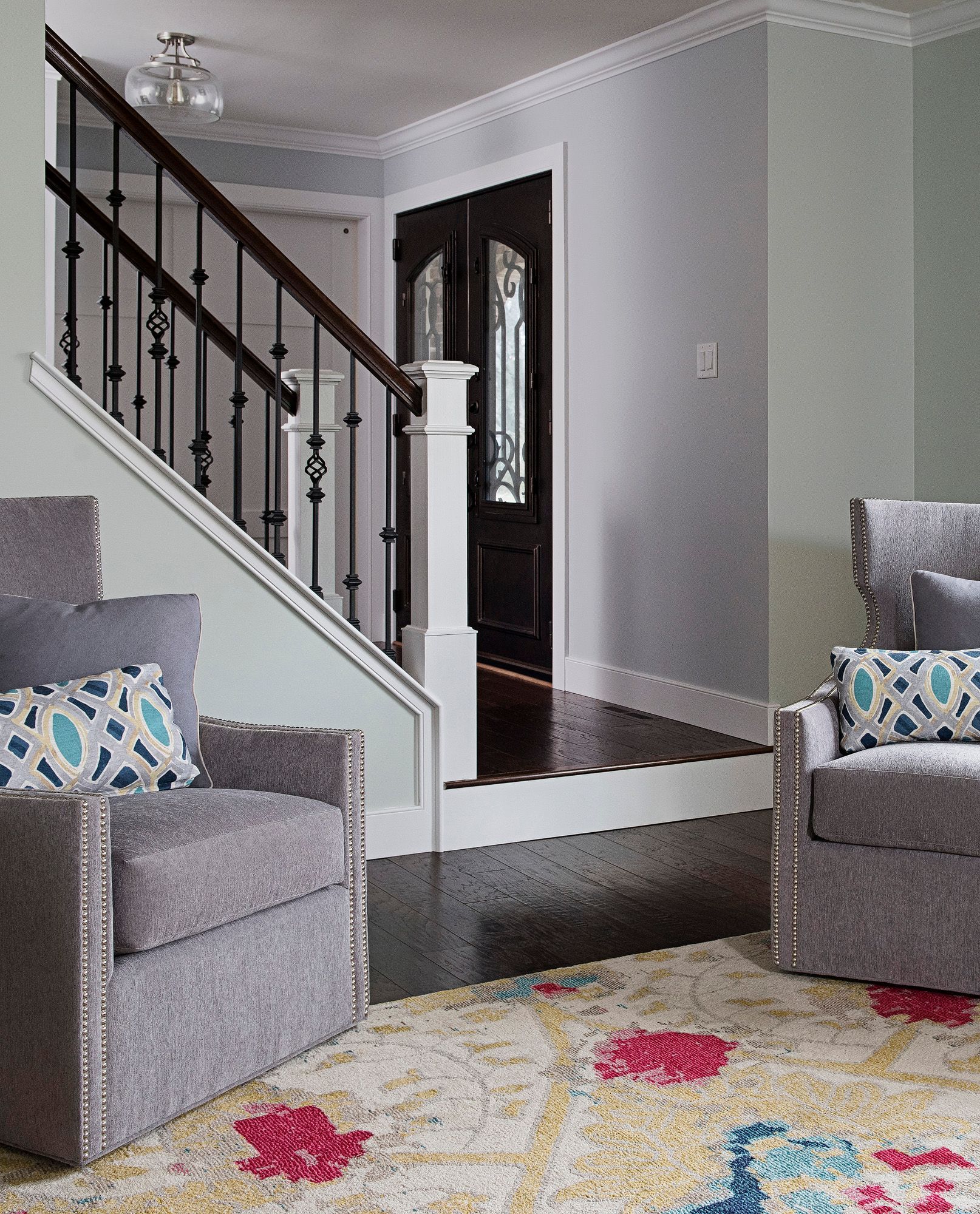 A living room with a staircase , chairs and a rug