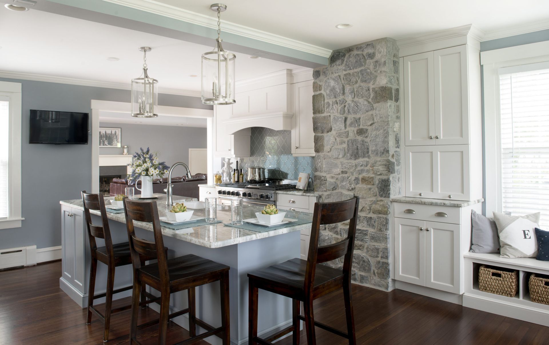 A kitchen with a large island in the middle and a stone wall.
