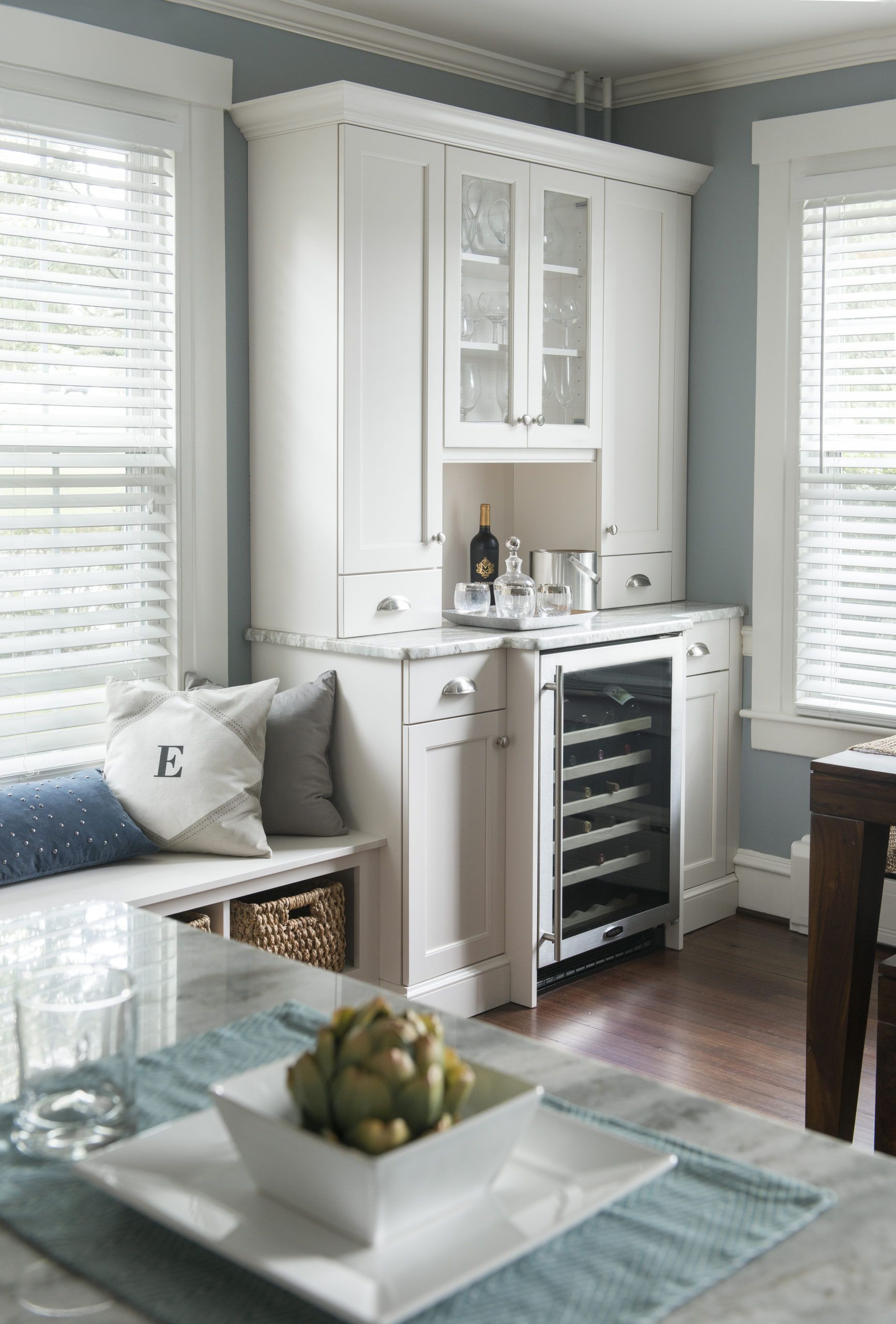 A living room with white cabinets and a bowl of fruit on the table