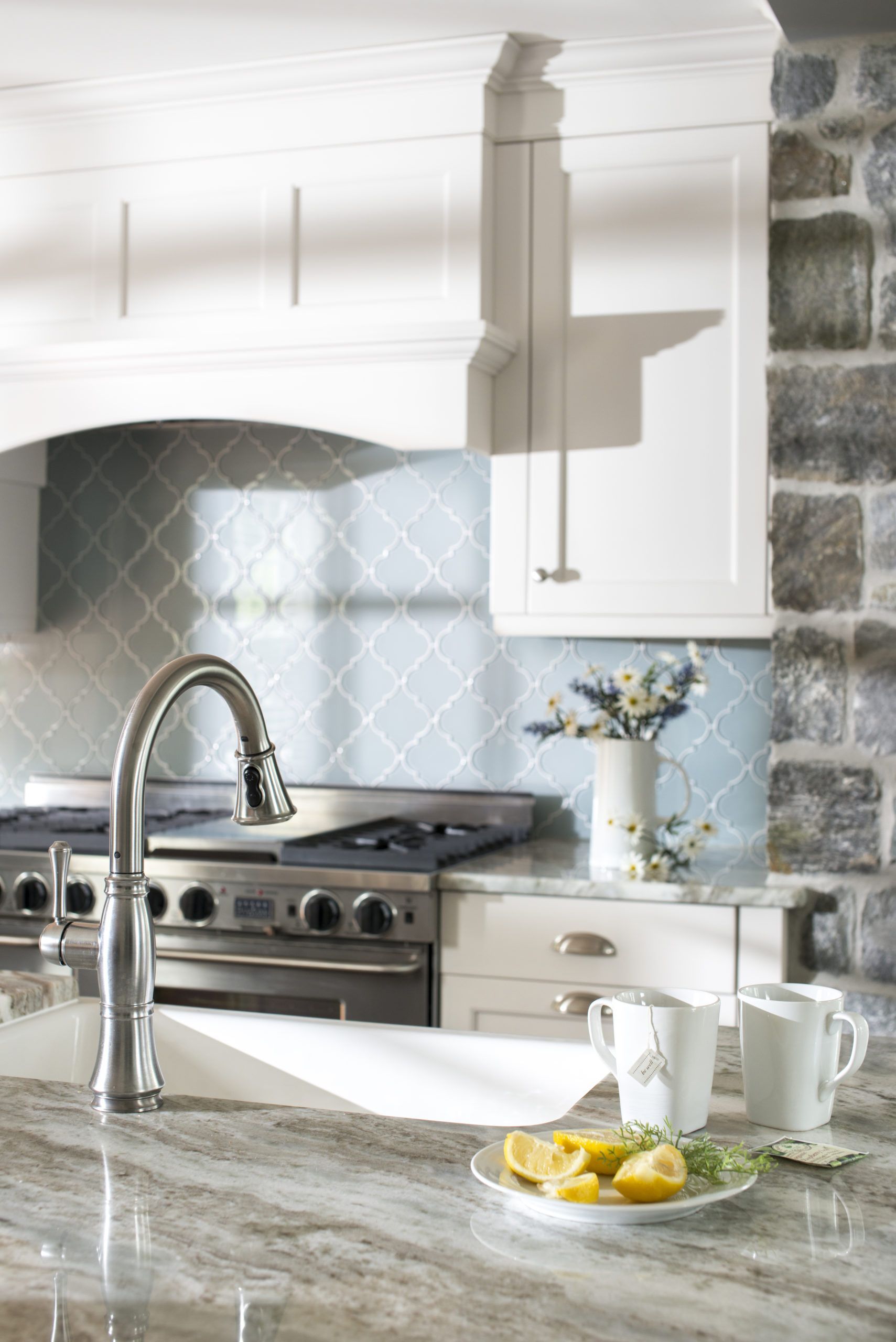 A kitchen with a sink , stove and a plate of lemons on the counter.