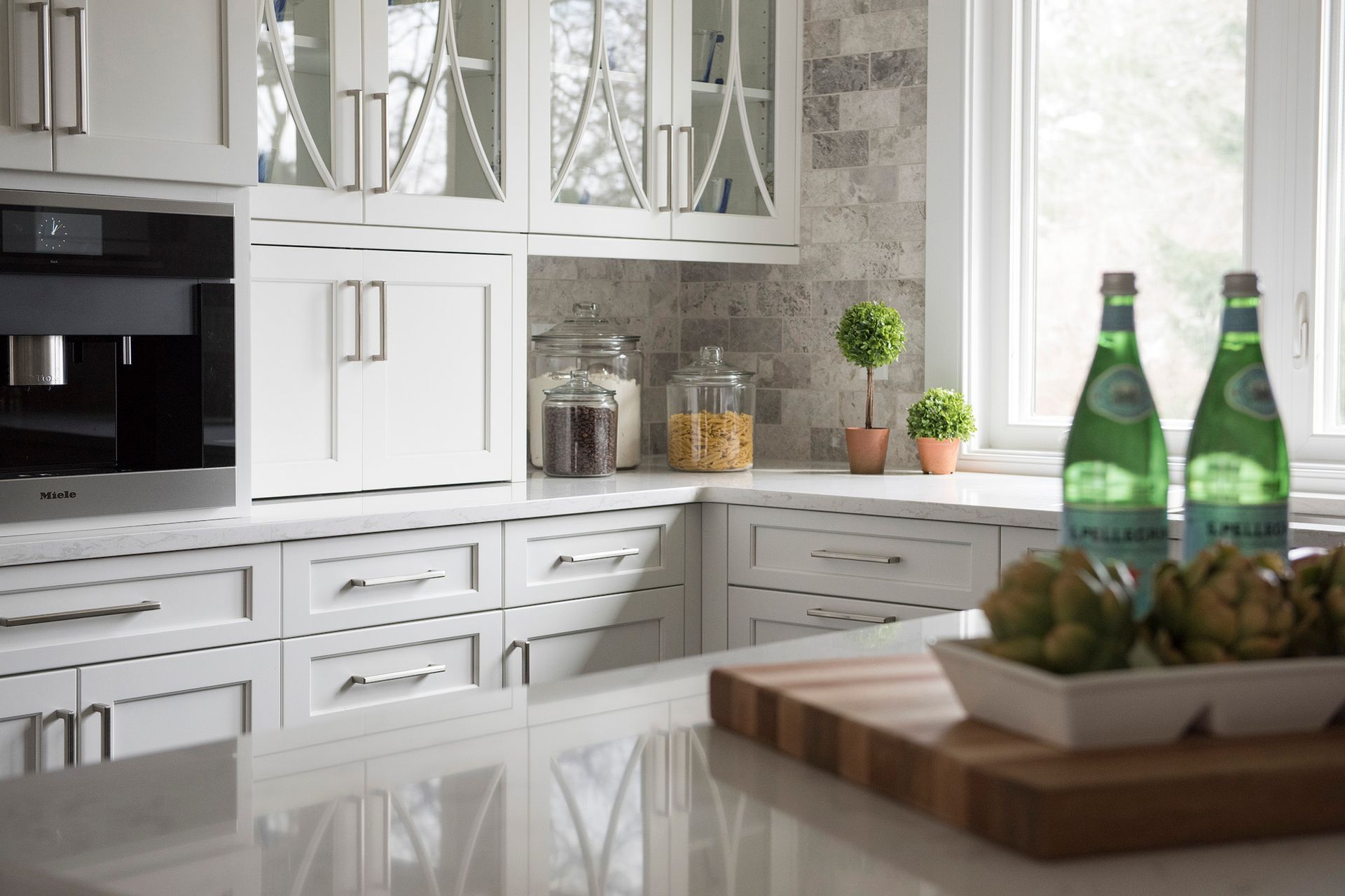 A kitchen with white cabinets and two bottles of water on the counter.