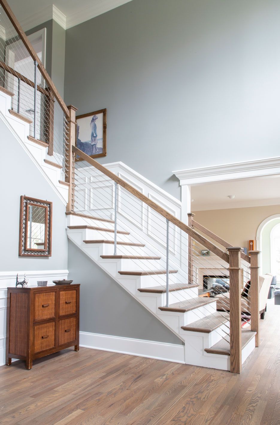 A staircase in a house with a wooden railing and a mirror on the wall.