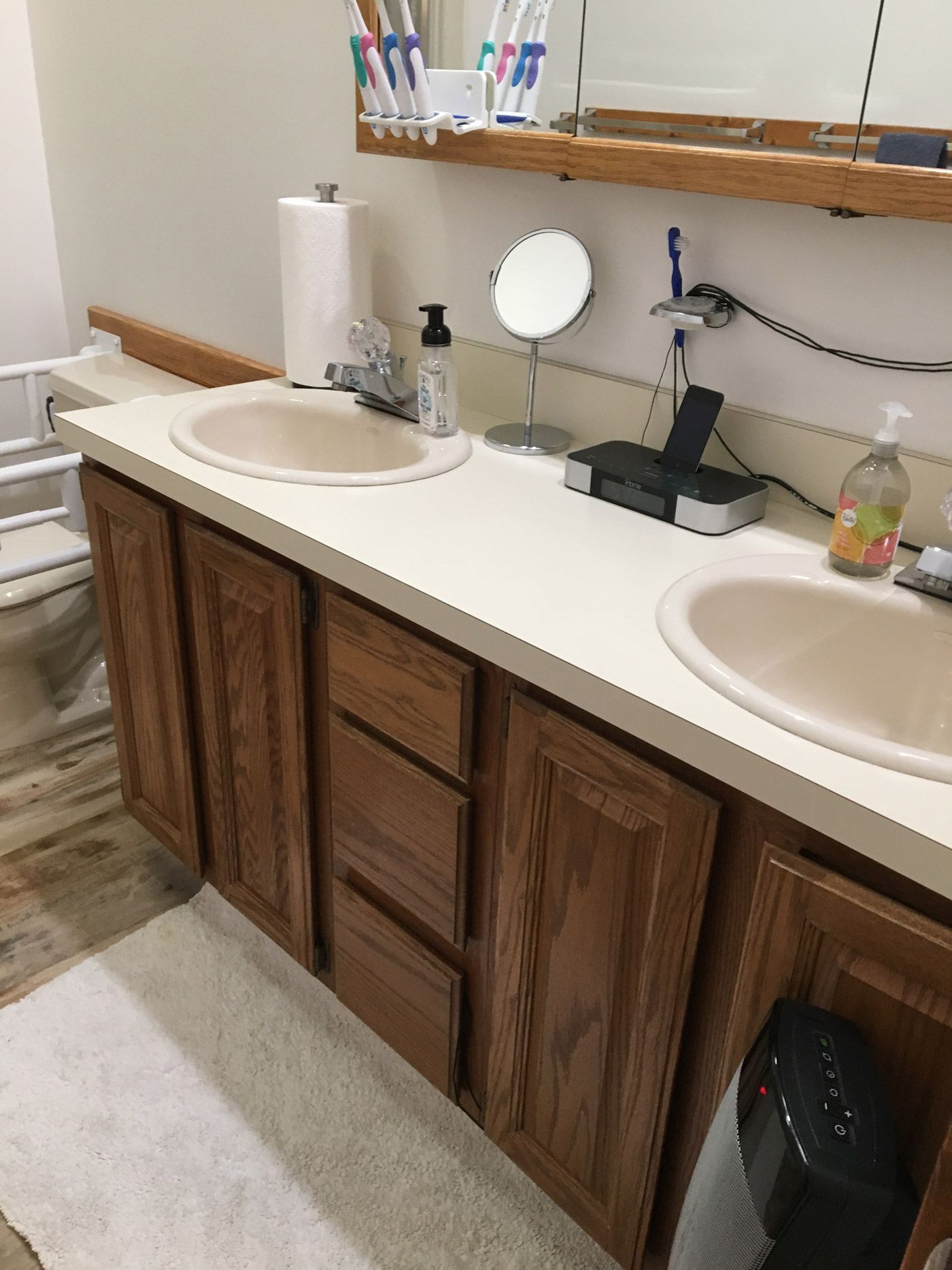 A double-sink bathroom vanity with light-colored countertops, wood cabinets, and various toiletries on the counter.