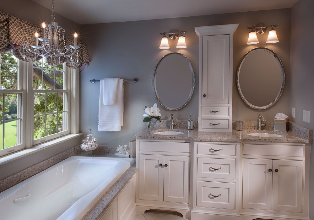 A bathroom with two sinks , two mirrors and a bathtub.