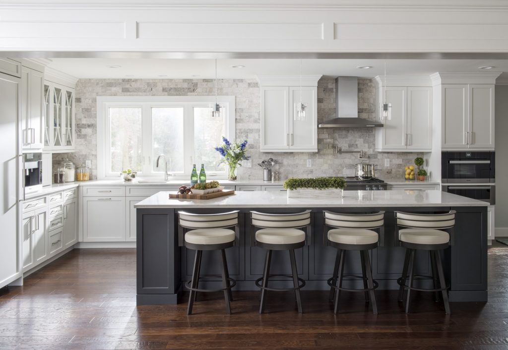 A kitchen with white cabinets and a large island with stools.