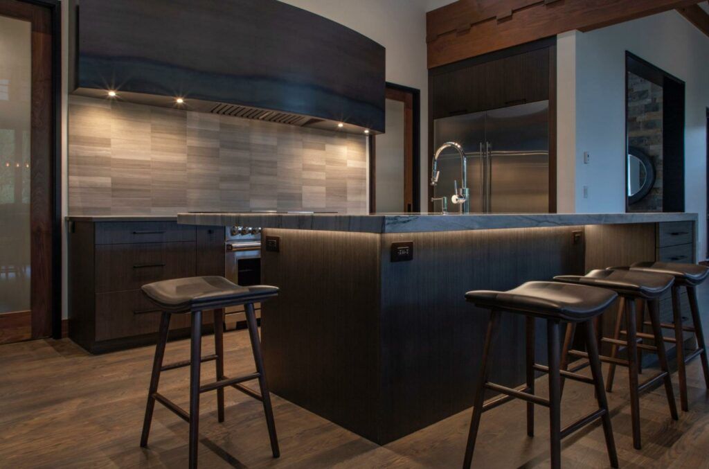 A kitchen with stools and a large island in the middle.