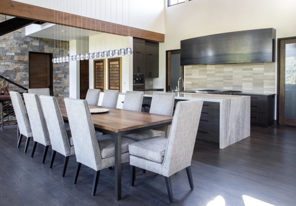 A dining room table with chairs and a kitchen in the background