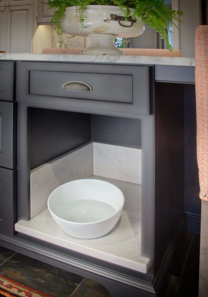 A white bowl is sitting on a shelf under a drawer in a kitchen.