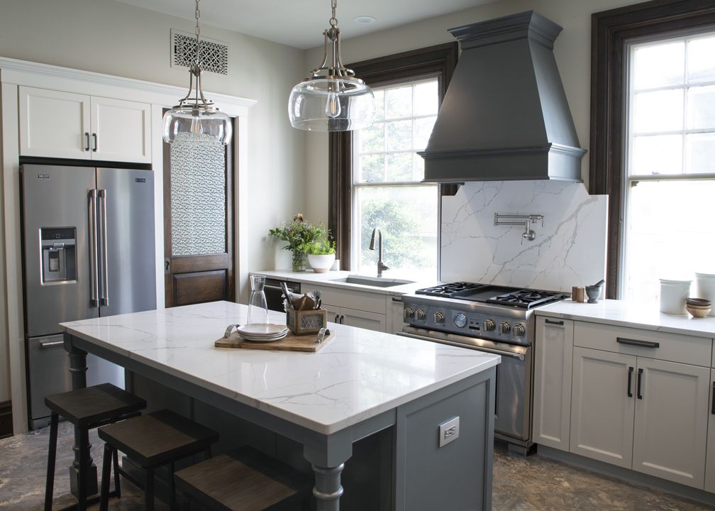 A kitchen with stainless steel appliances and a large island in the middle.