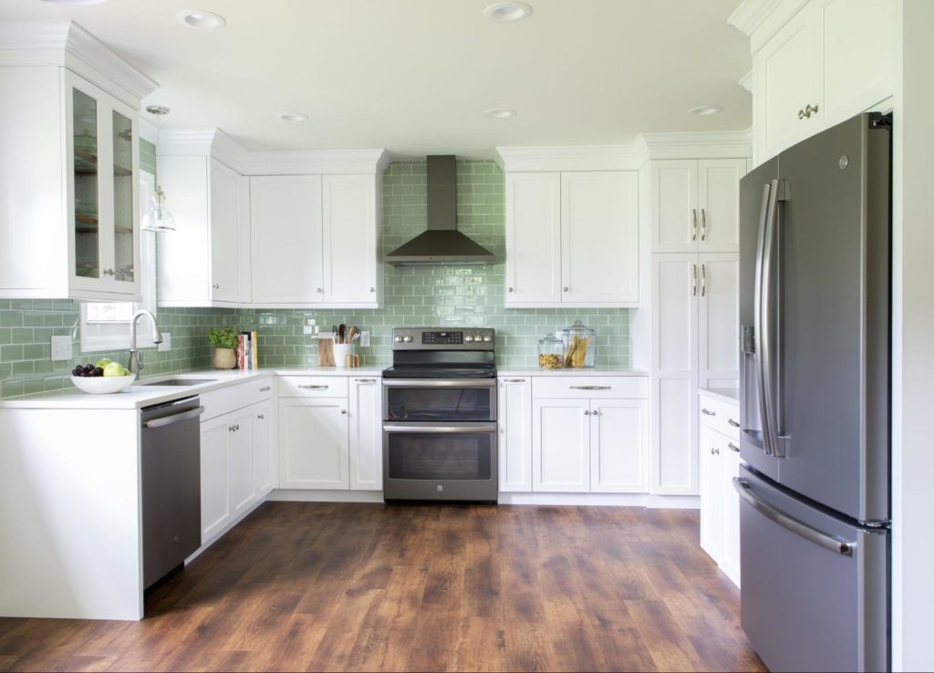 A kitchen with white cabinets , a stove , a refrigerator , and a dishwasher.