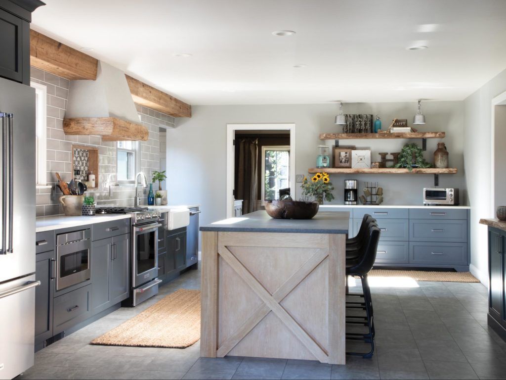 A kitchen with a large island in the middle and stainless steel appliances.