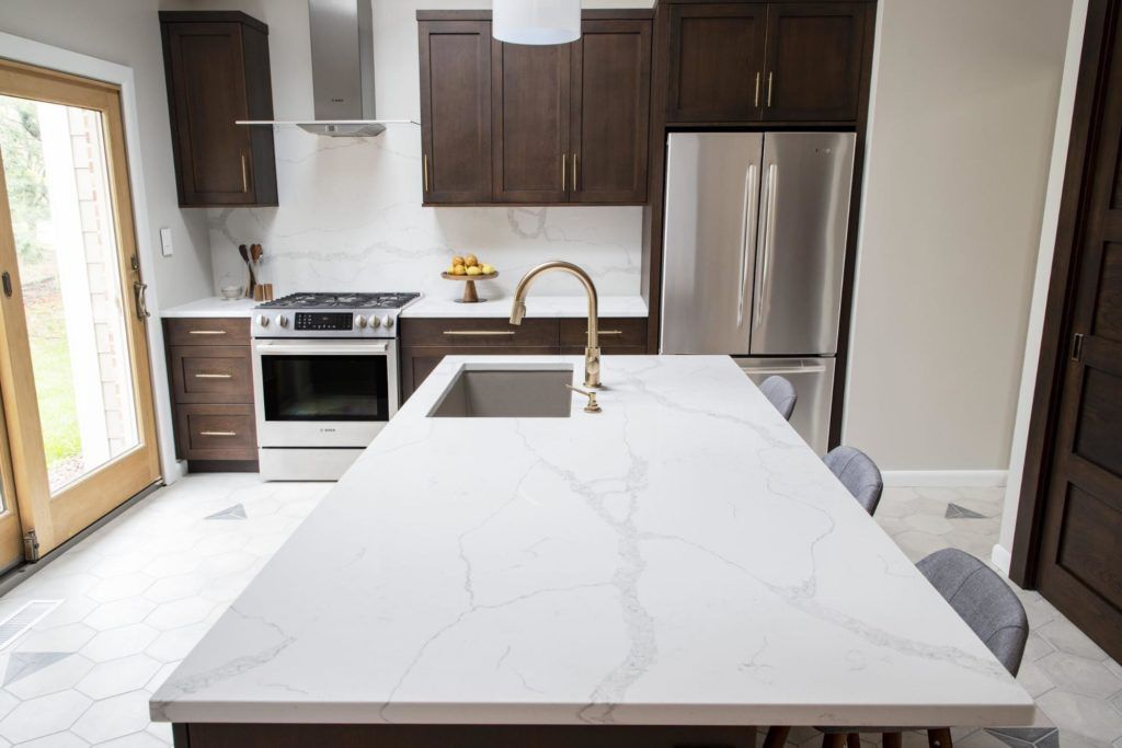 A kitchen with stainless steel appliances and a large island with a sink.