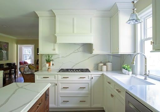 A kitchen with white cabinets , a stove top oven , a sink , and a window.