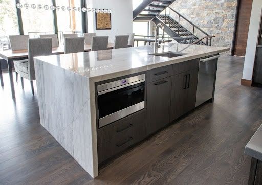 A kitchen with a large island and a staircase in the background.