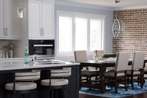 A kitchen with a dining table and chairs and a brick wall.