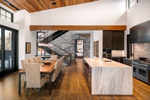 A kitchen and dining room in a house with a large island in the middle.