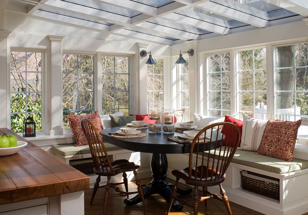 A dining room with a table and chairs and a window seat.