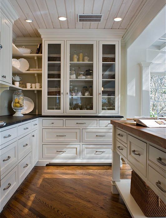 A kitchen with white cabinets and glass doors