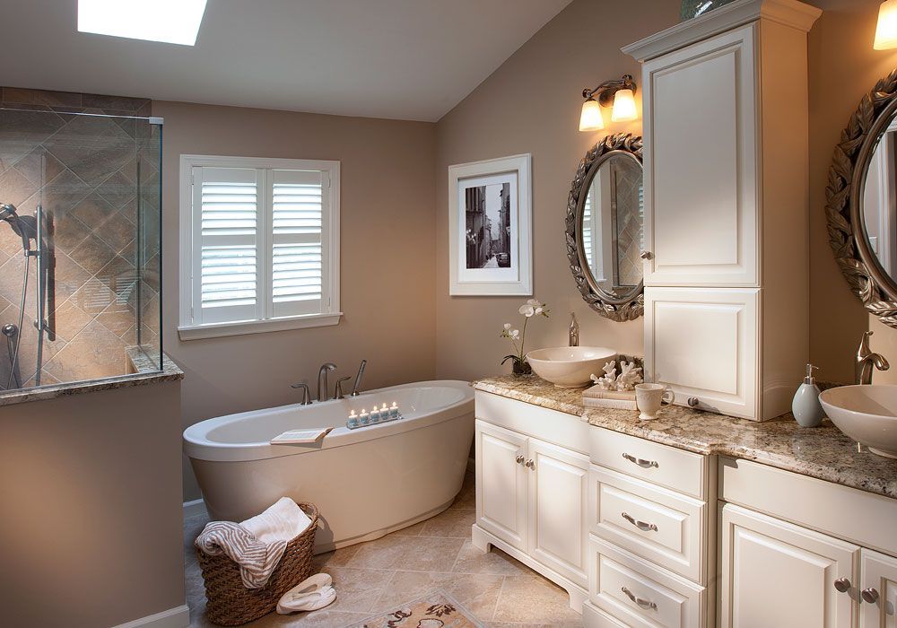 A bathroom with a tub , sink , mirror and cabinets