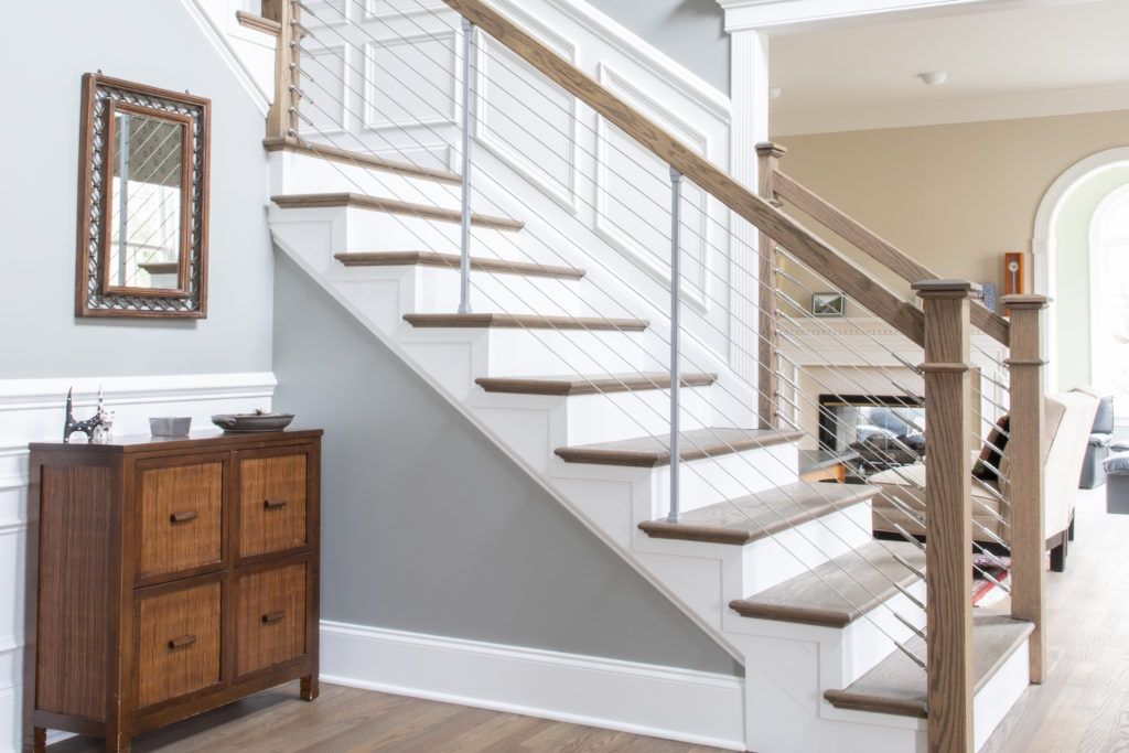 A white staircase with wooden steps and a metal railing in a living room.
