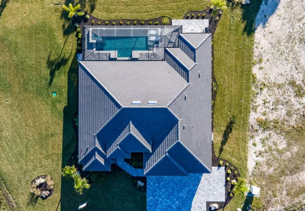 Overhead view of a house with a pool, gray roof, and green lawn.