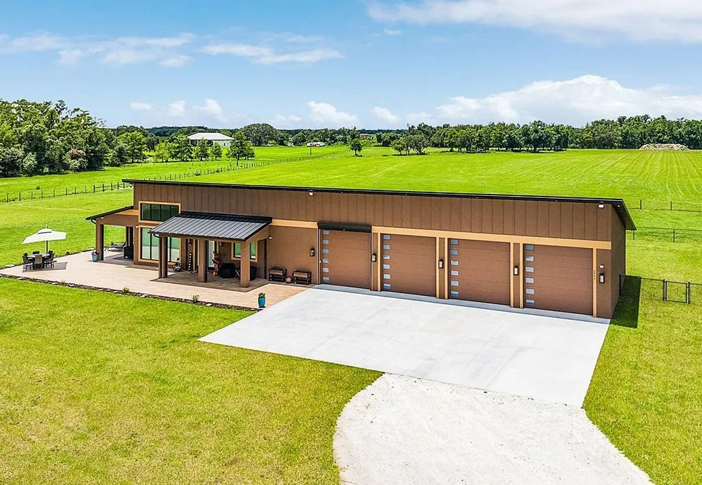 Brown building with multiple garage doors and a patio on green lawn.