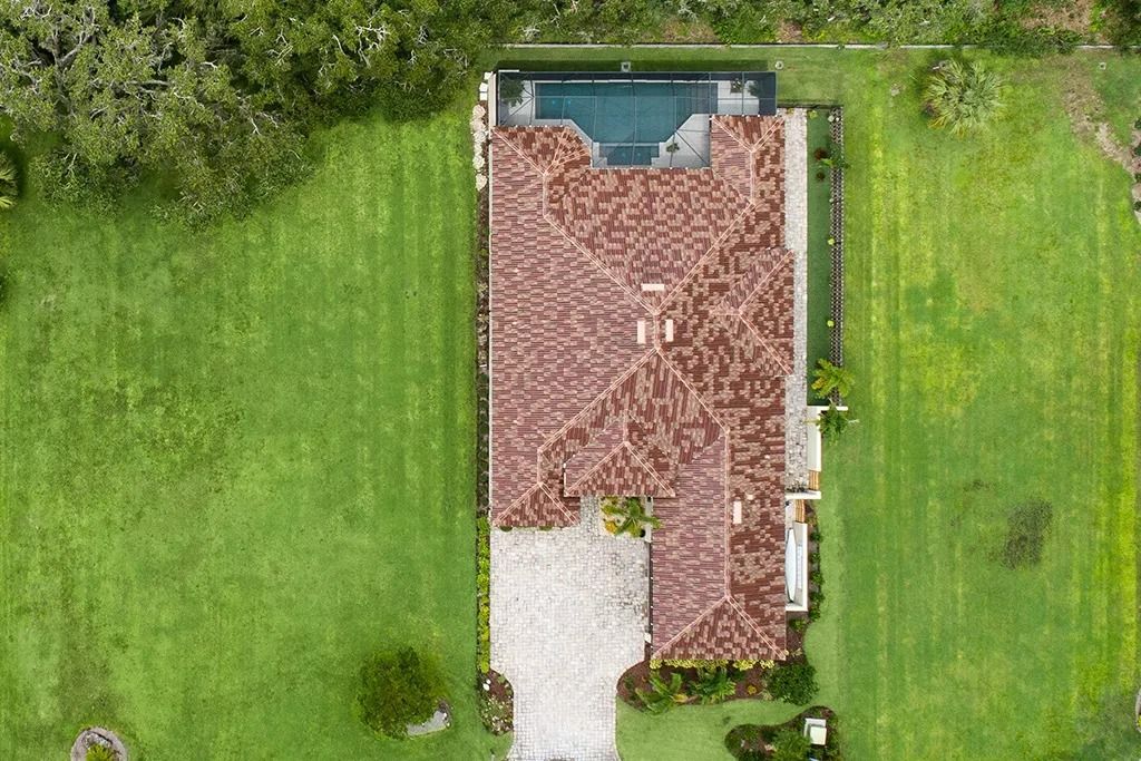 Overhead view of a house with a tile roof, pool, and green lawn.