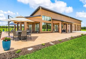 Modern home with patio, table, chairs, and umbrella on a sunny day.