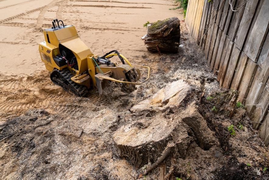 Yellow excavator clearing muddy debris beside a wooden wall on a flooded construction site