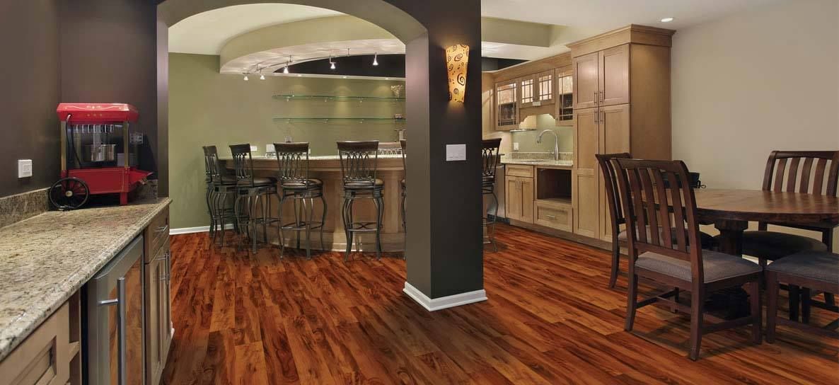 Interior of a finished basement with a bar, dining area, and popcorn machine on a granite countertop.