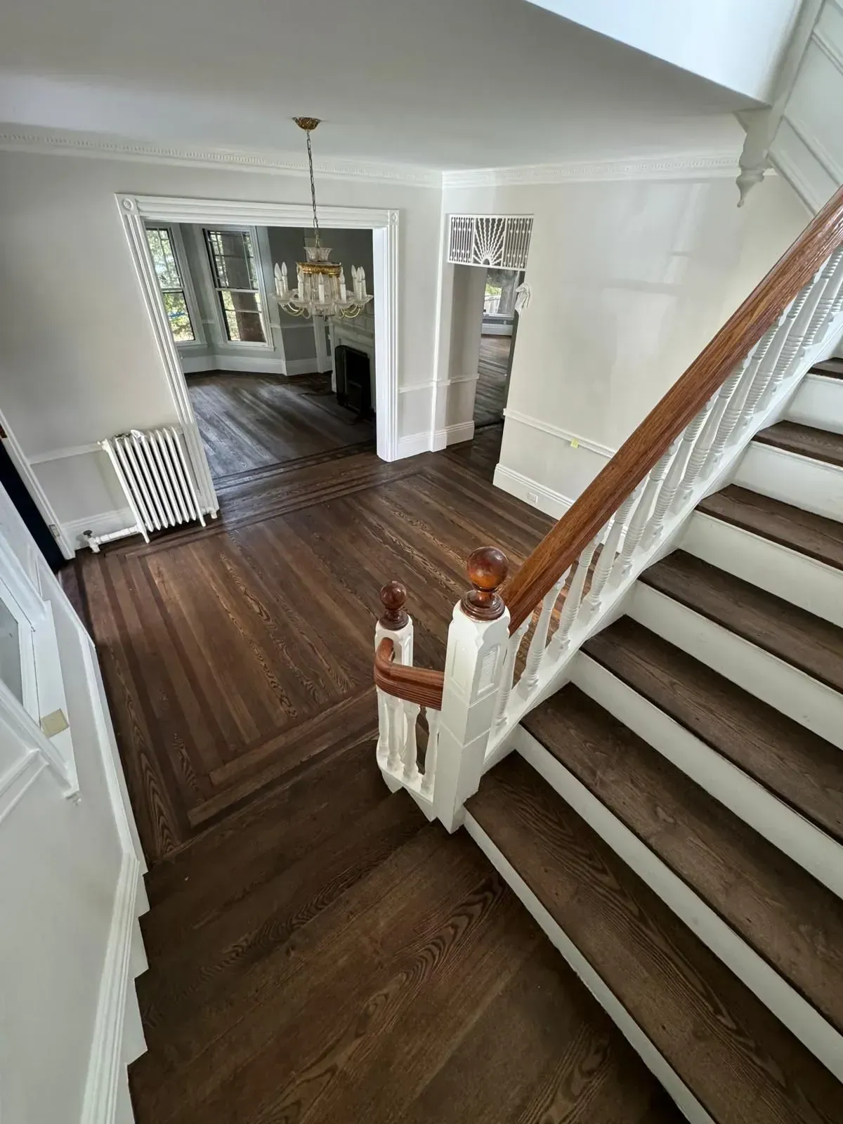 Entryway with dark wood floors, staircase, and view into a living room with a fireplace.
