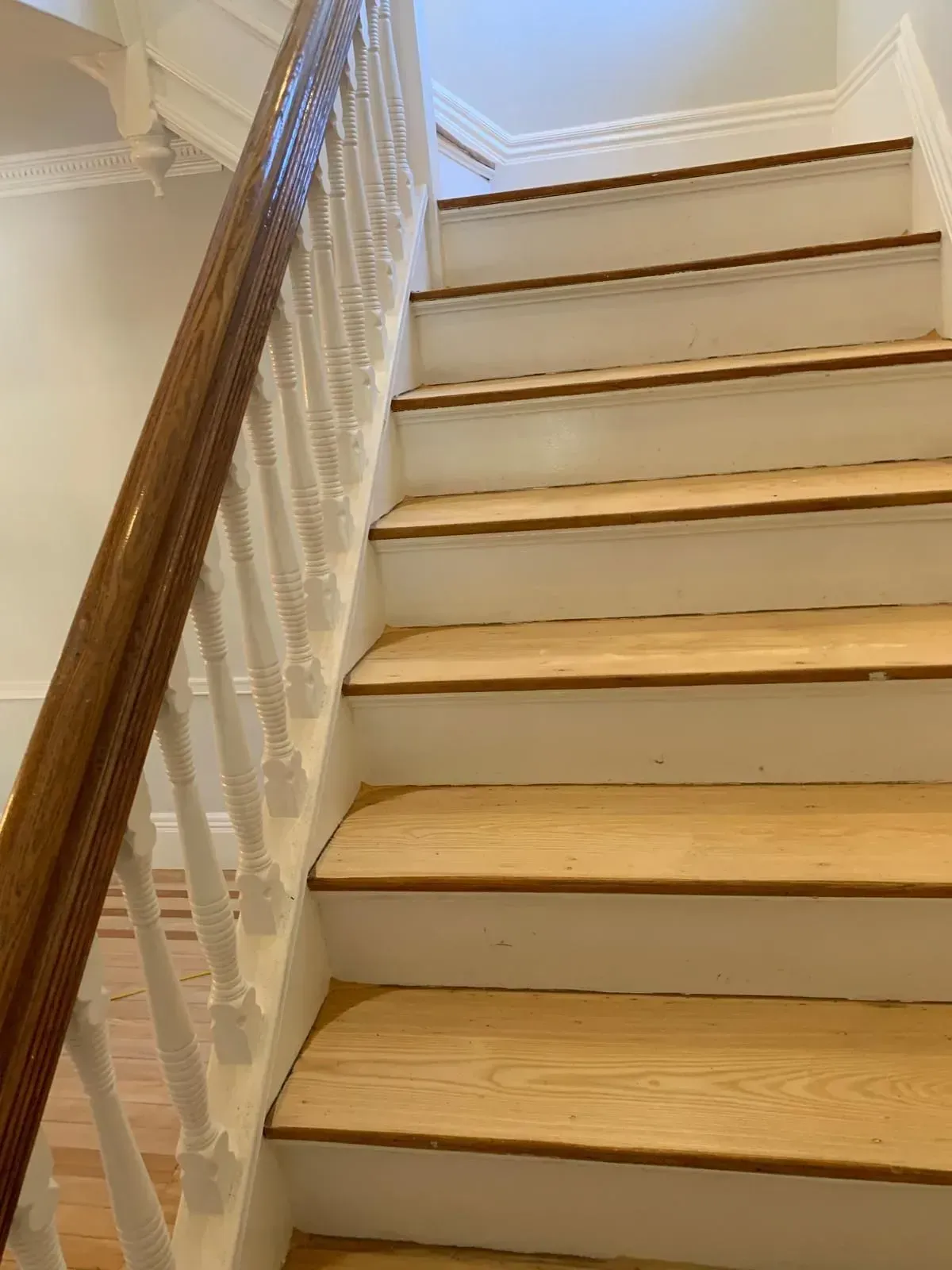 Wooden staircase with white risers, wooden treads, and a stained handrail.