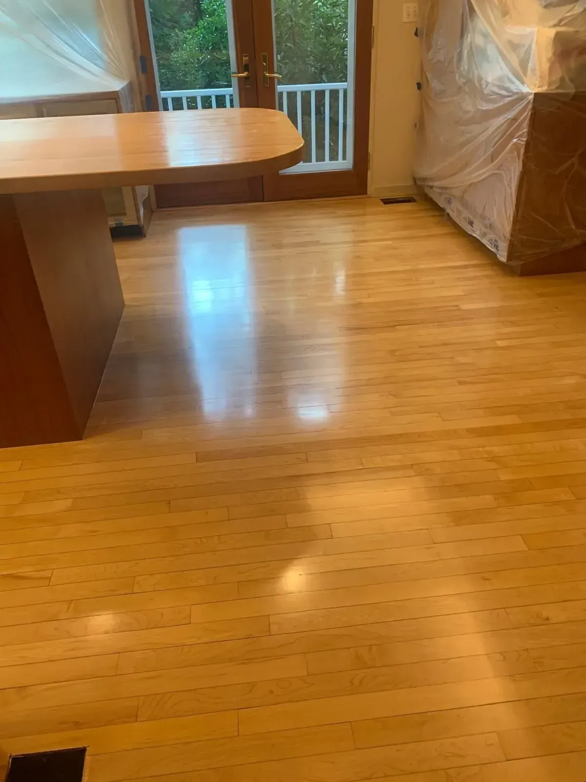 Hardwood floor in kitchen with a wooden island and sunlight reflecting on the floor.