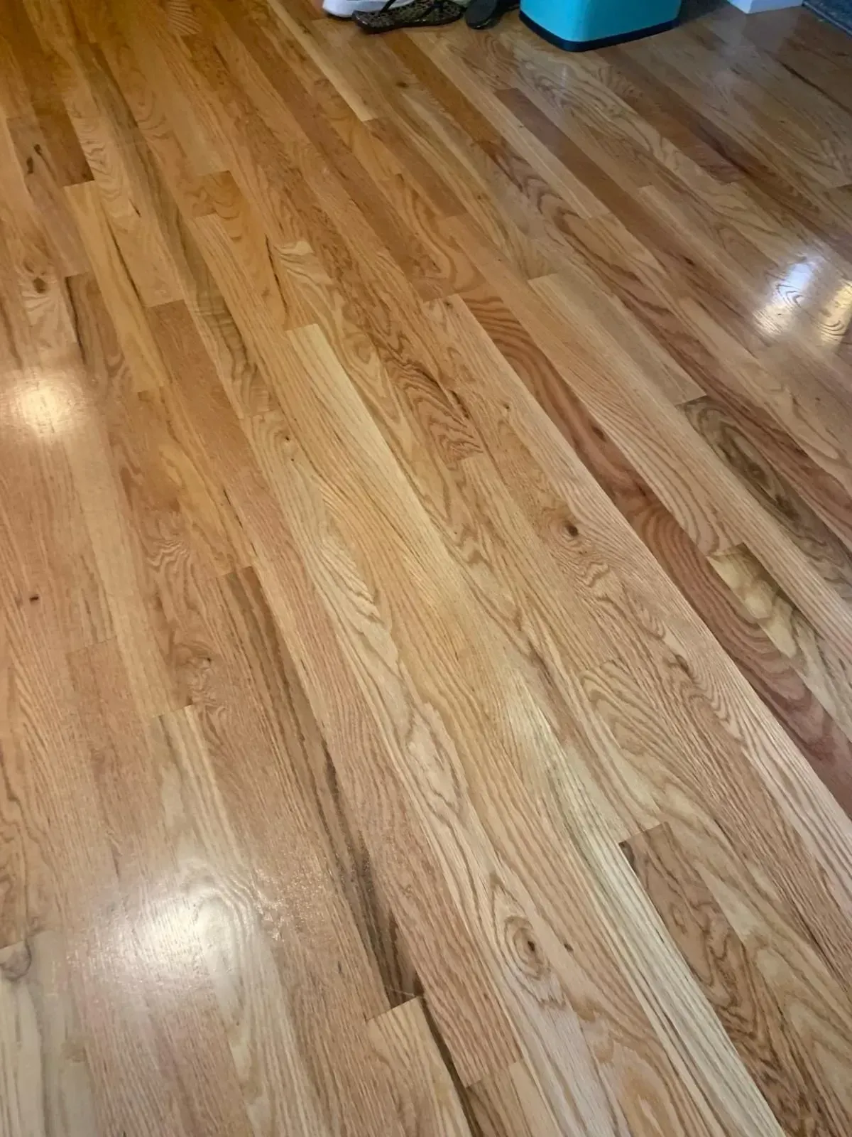 Hardwood floor with a reddish-brown finish, angled towards the upper right.